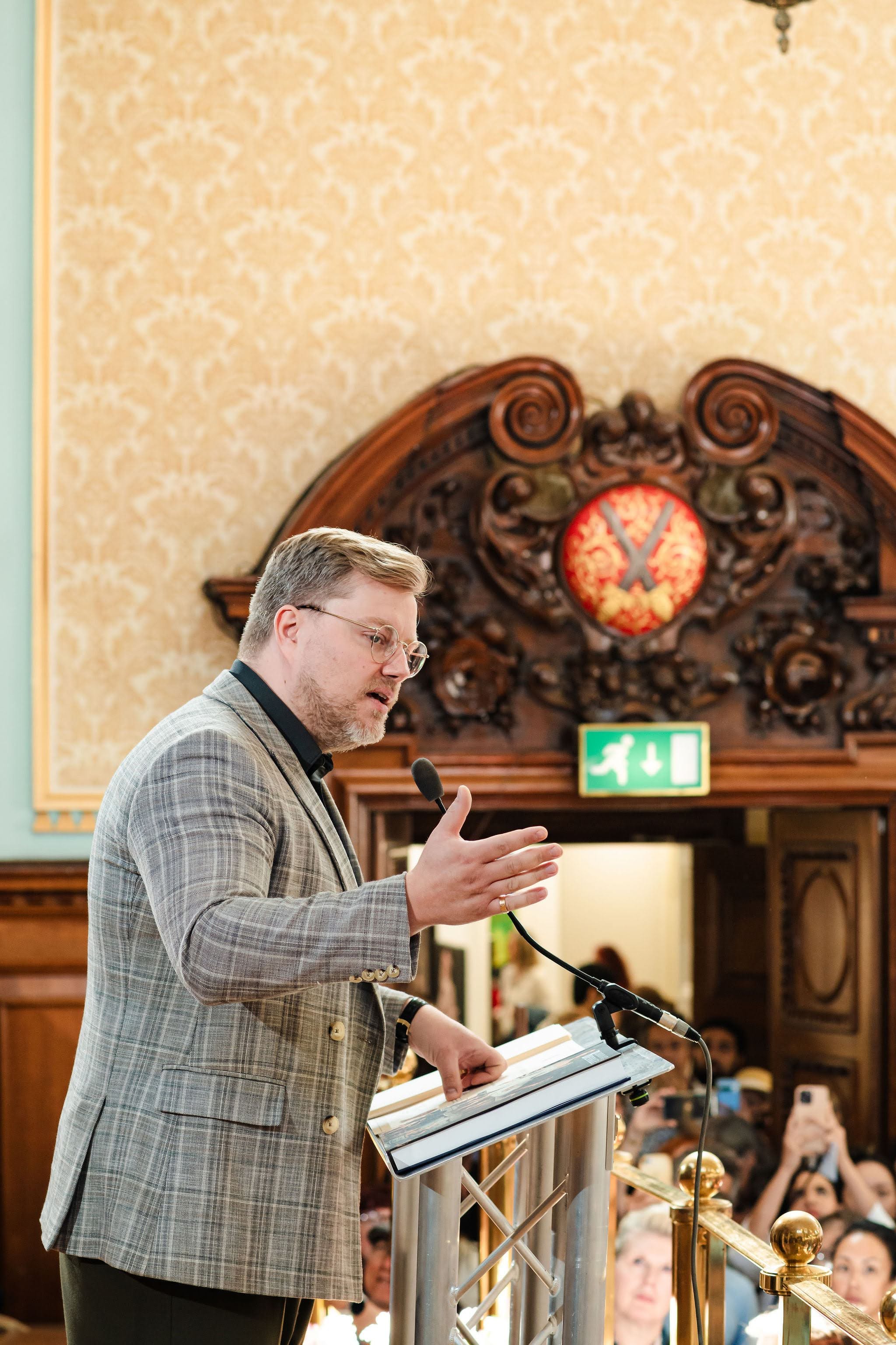 An address given from the podium during the Biennale, the carved and gilded panelling of the hall behind.