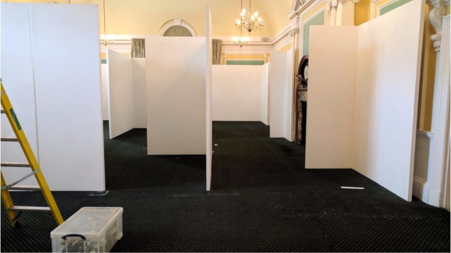 The run of white partition walls taking shape across the carpeted hall.
