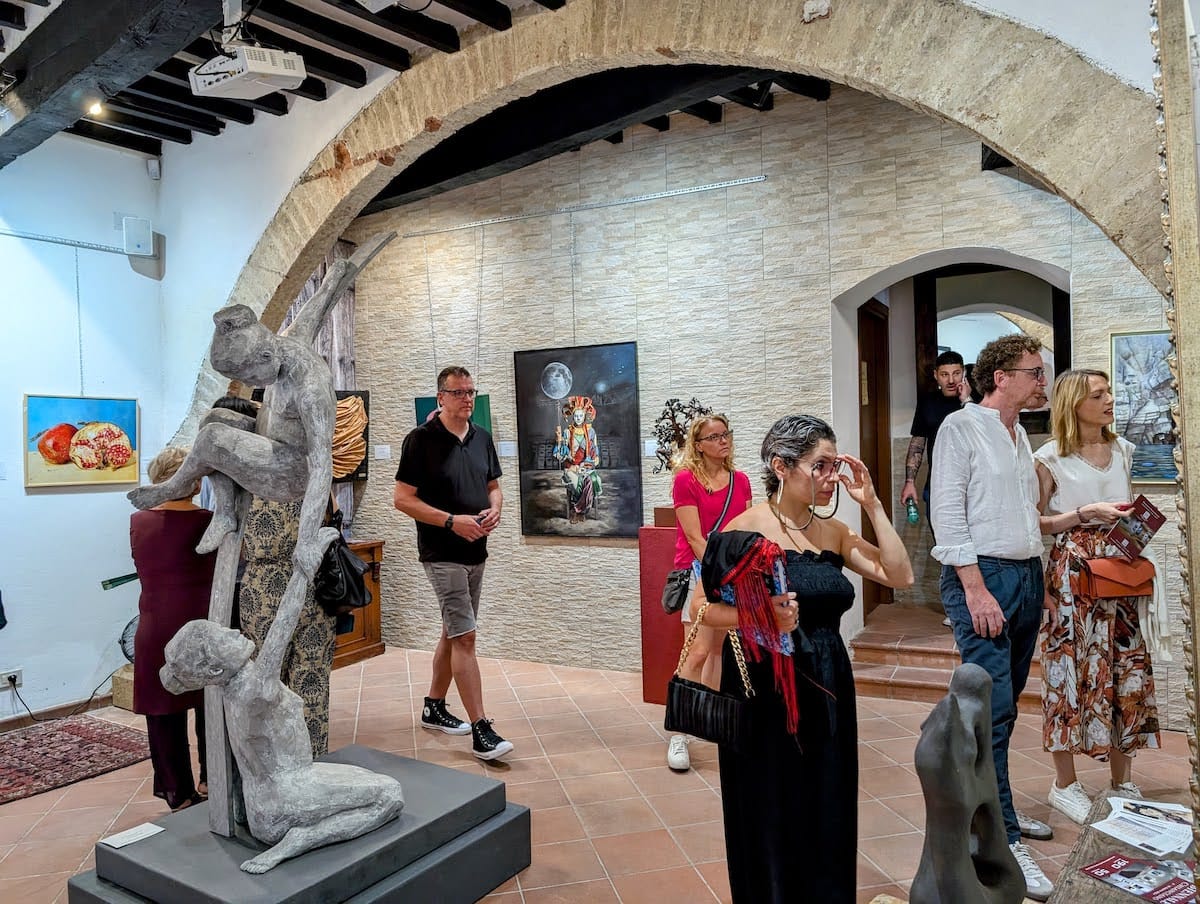 Sculpture beneath the stone arch, the galleries busy behind it.