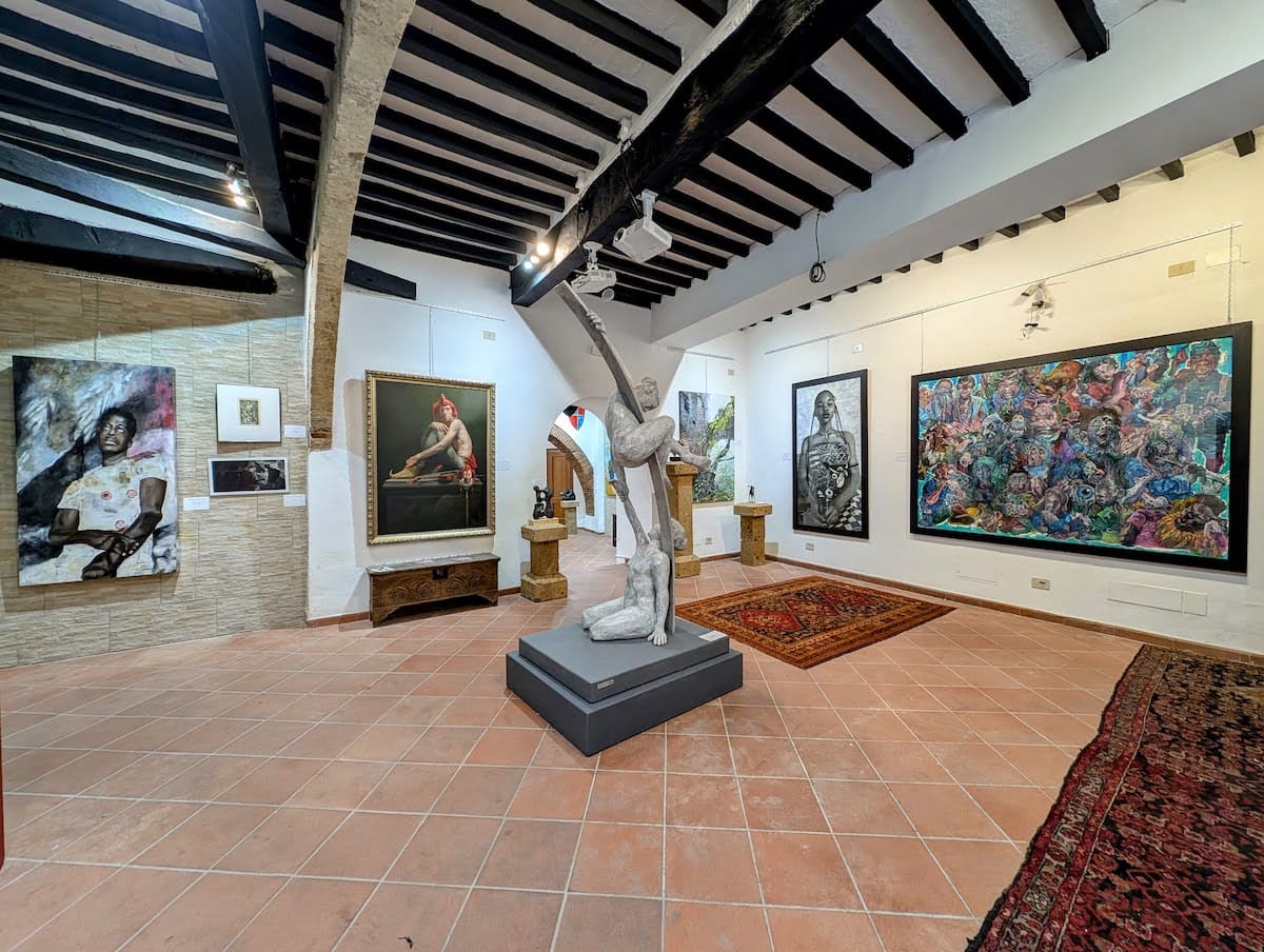 A marble figure under the beams, paintings either side.
