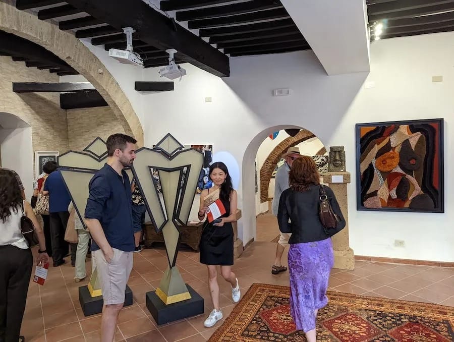 A pair of visitors with the metal figures in the arched gallery.