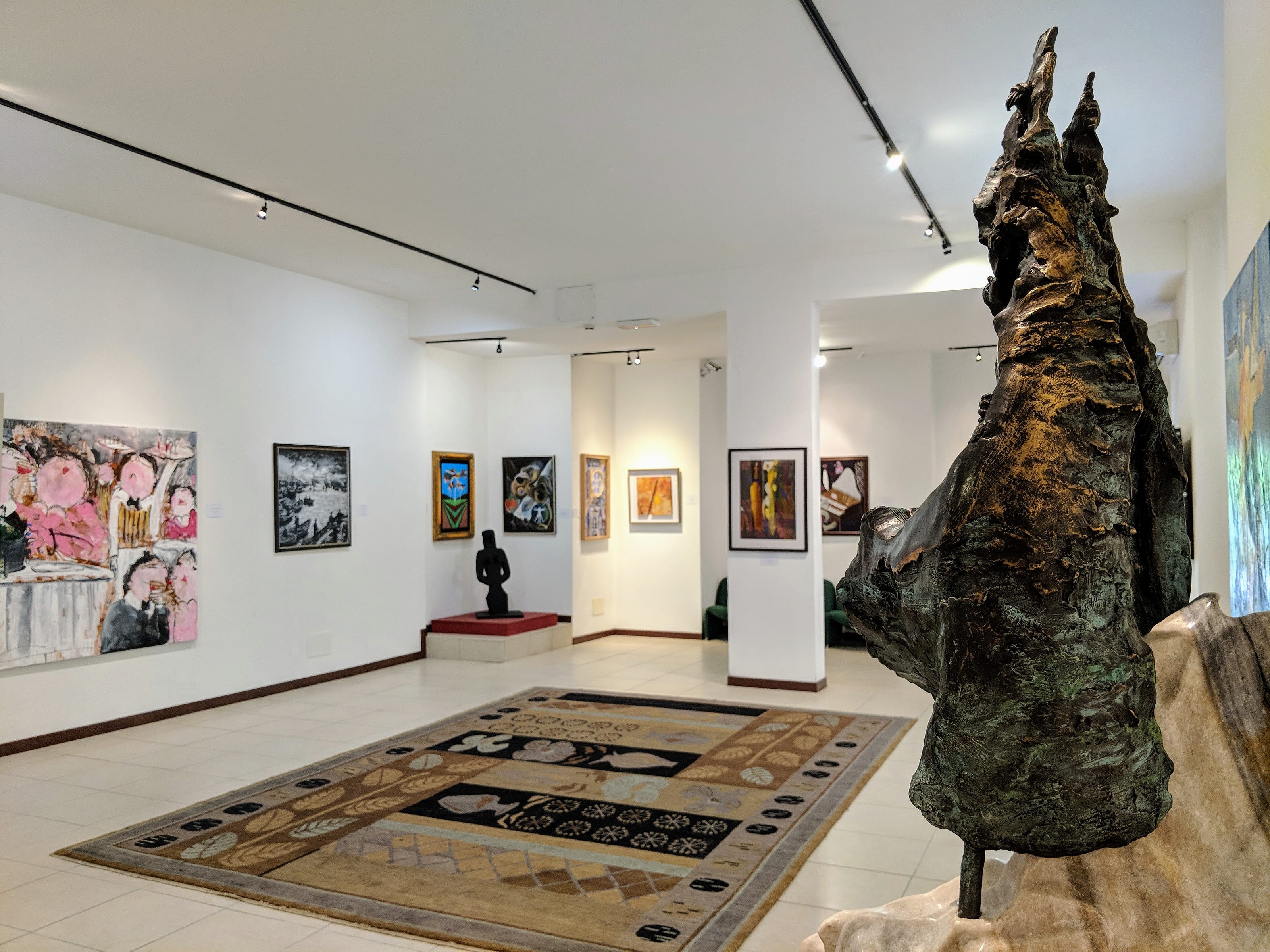 Inside the Chianciano Art Museum, a bronze rising over the carpeted floor.