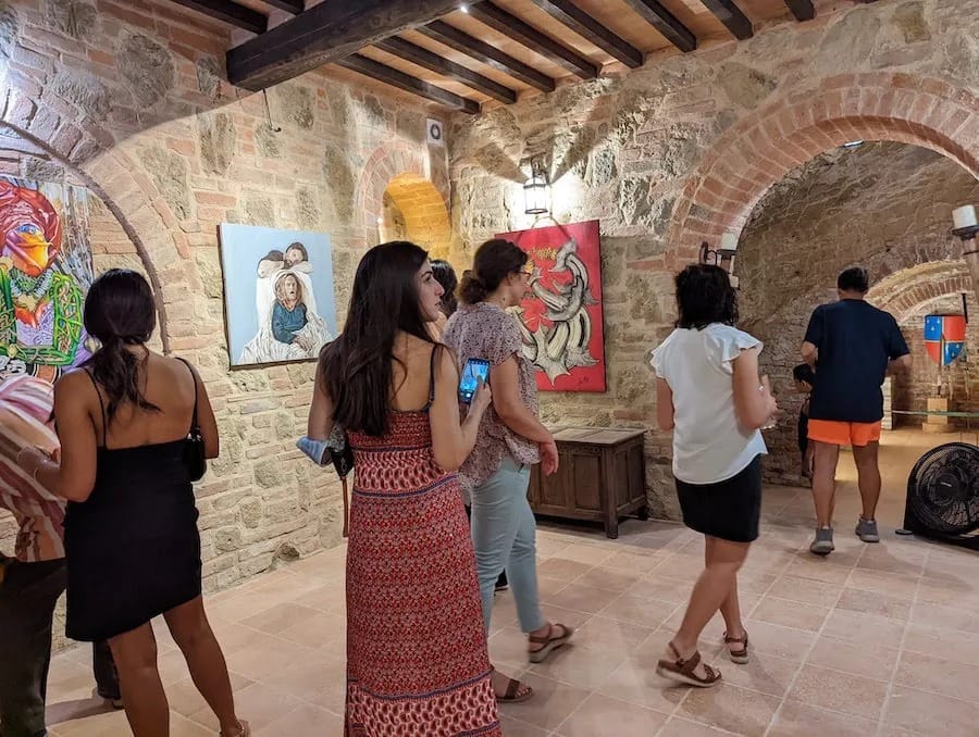 The stone-walled gallery, paintings bright against the masonry.