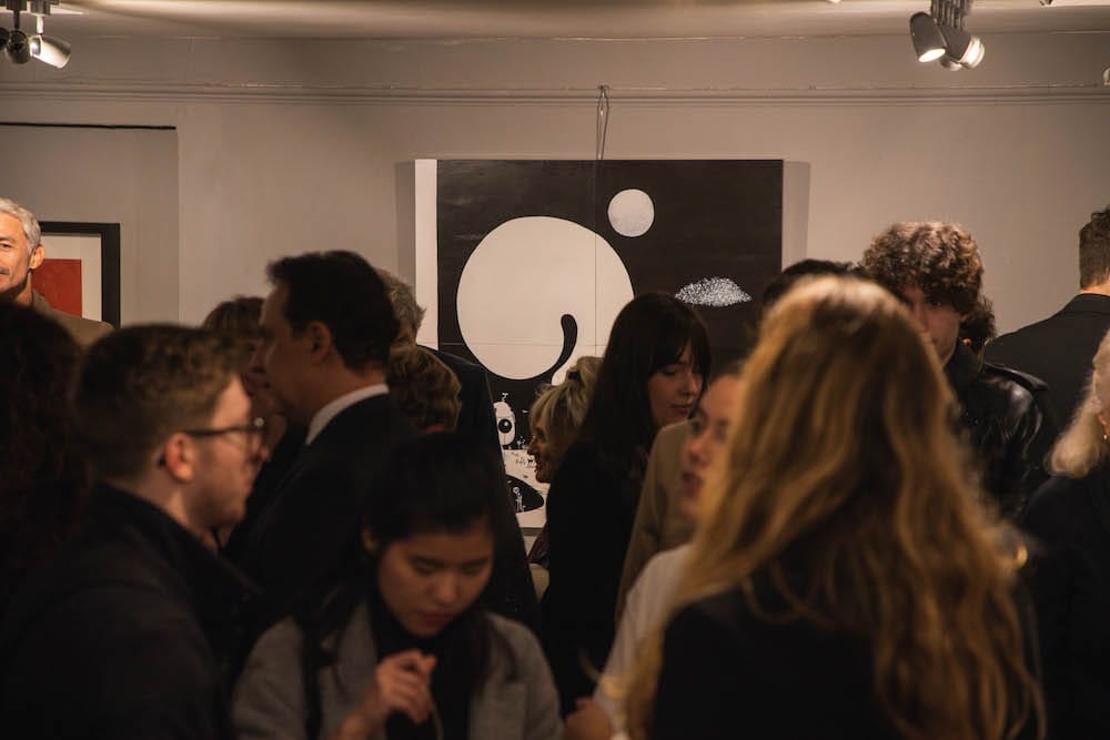 The crowd gathered at the monochrome canvas.