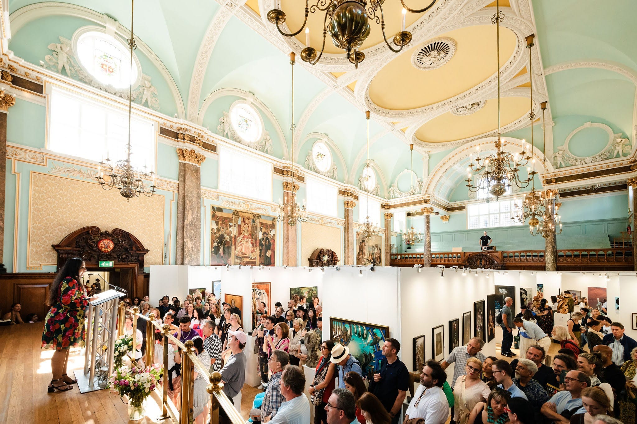 The main hall during the Seventh Edition, full for an address beneath its painted and gilded vault and chandeliers.