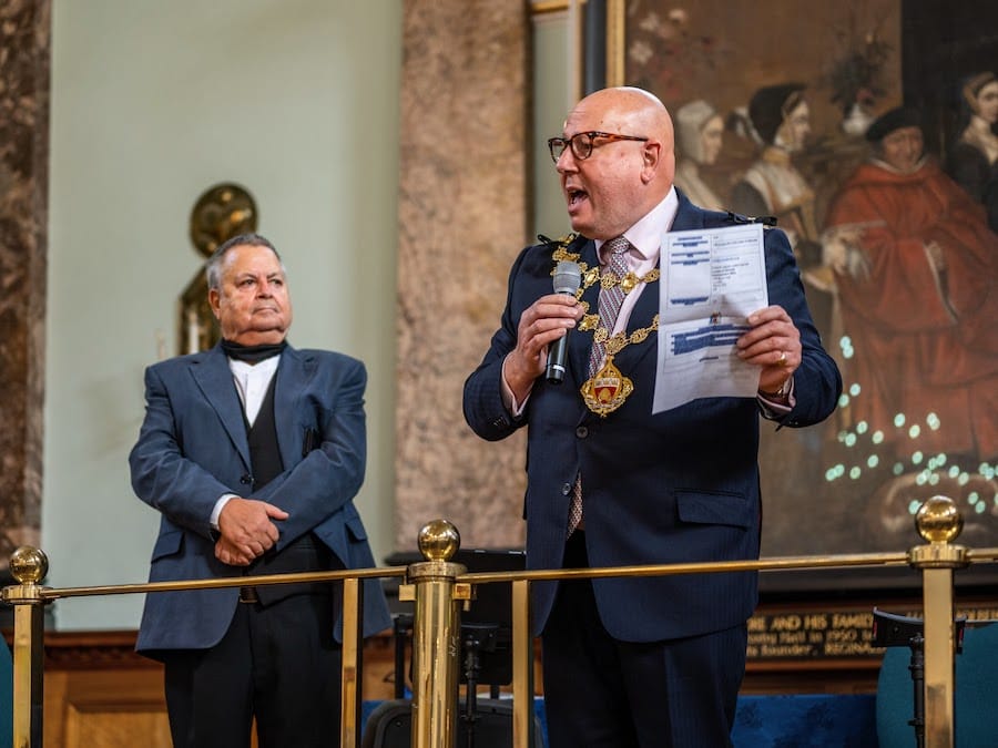 The Mayor of Kensington and Chelsea reading out the raffle results on the balcony.