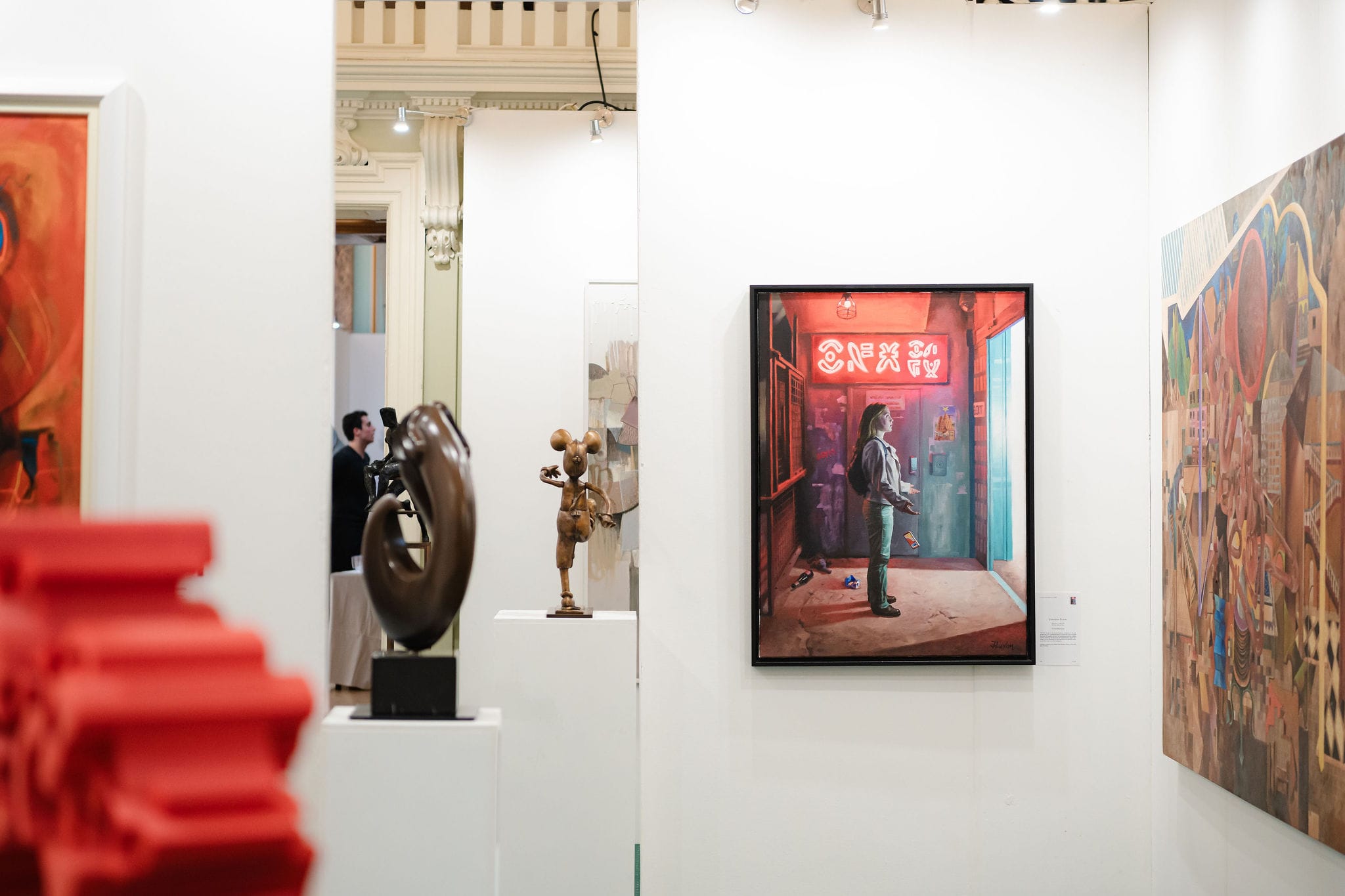 A painting of a neon-lit doorway hung in the exhibition, sculpture on plinths beyond it.