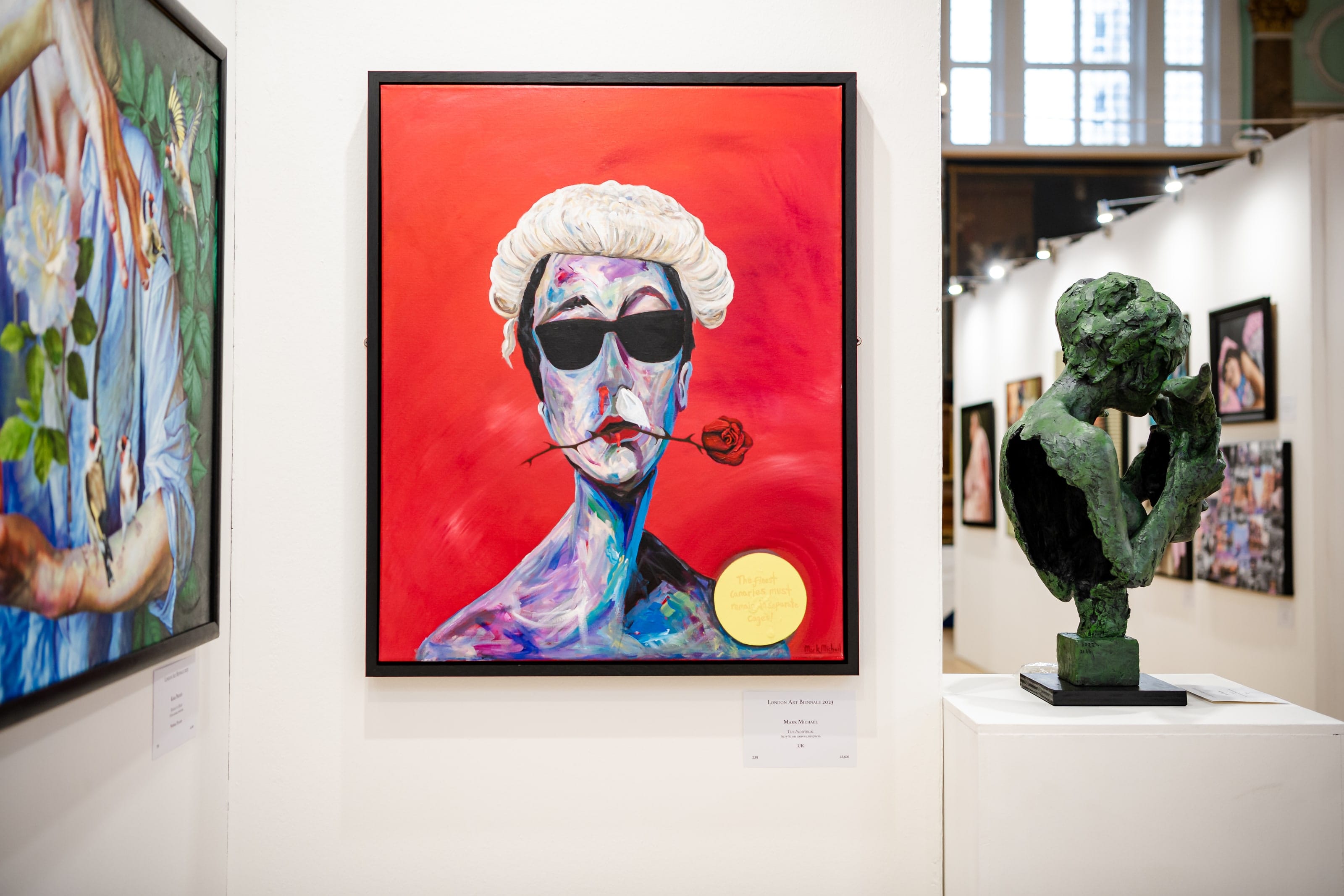 A portrait on a vivid red ground hung in the exhibition, a bronze bust on a plinth beside it.