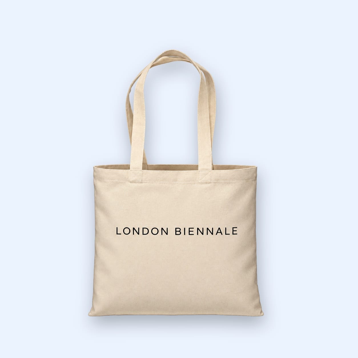 A natural cotton tote bag printed London Biennale, against a pale blue ground.
