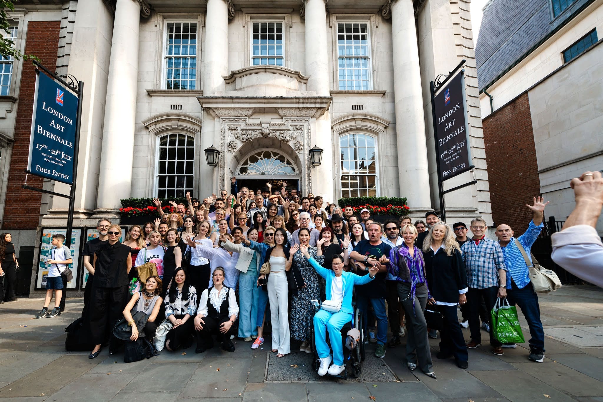 Exhibiting artists gathered on the steps of Chelsea Old Town Hall beneath its columns and the Biennale banners.