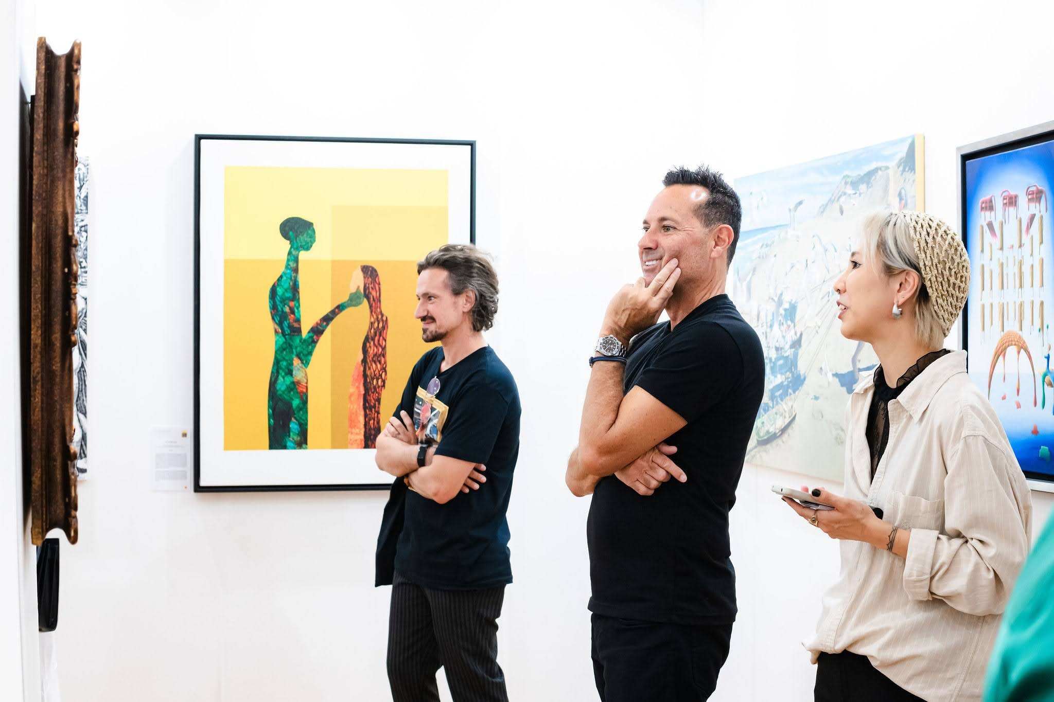 Visitors standing together in front of a framed print in the exhibition, caught mid-conversation.