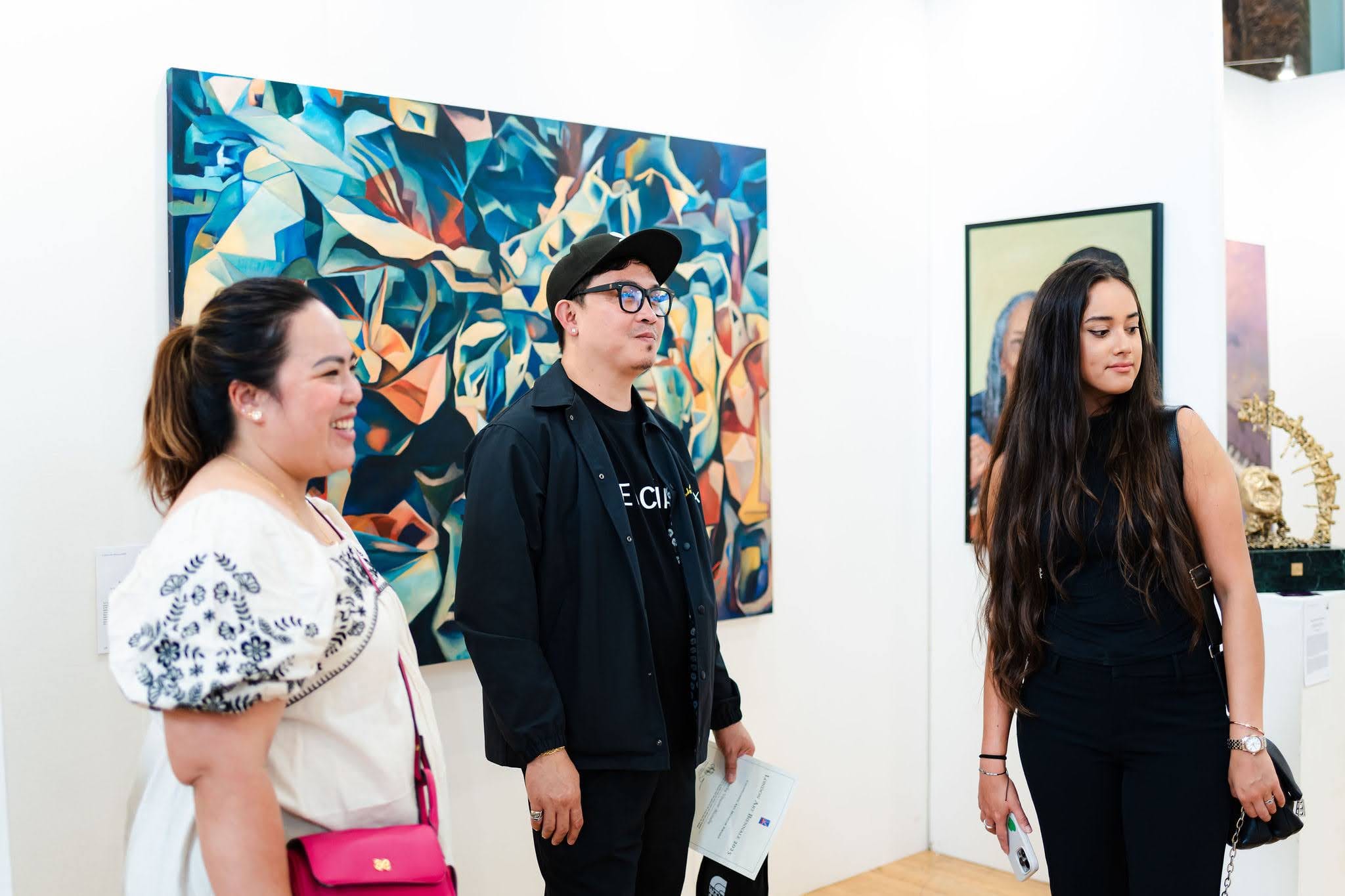 Visitors standing in front of a large abstract painting during the exhibition, a catalogue in hand.